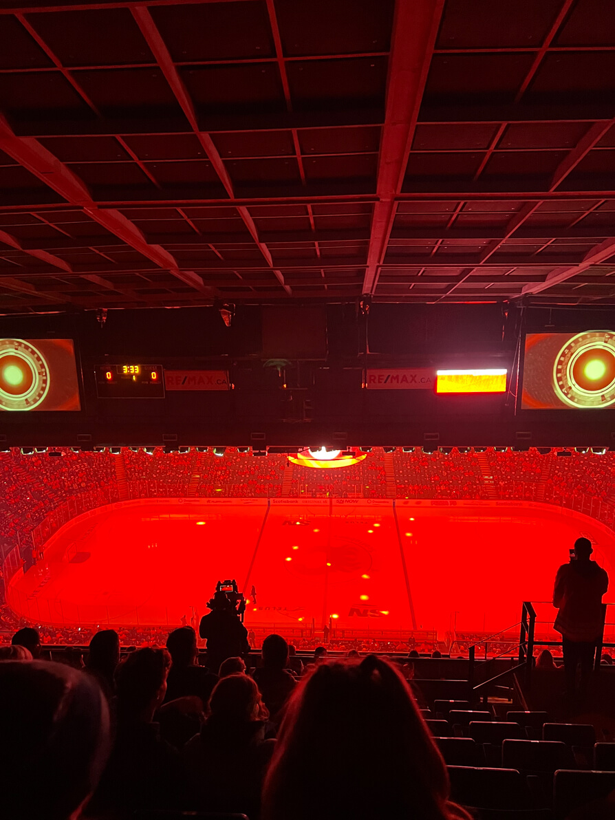 Image of Calgary Flames playing Winnipeg Jets at Saddleback stadium in Calgary. Image is from high seats with the stadium in complete red lights and players on.