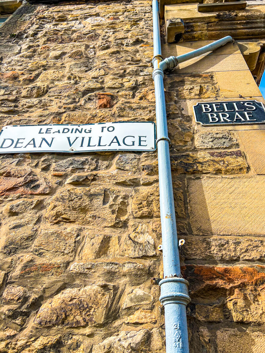 image of two street signs saying 'leading to Dean Village' and 'Bells Brae' in Dean Village Edinburgh