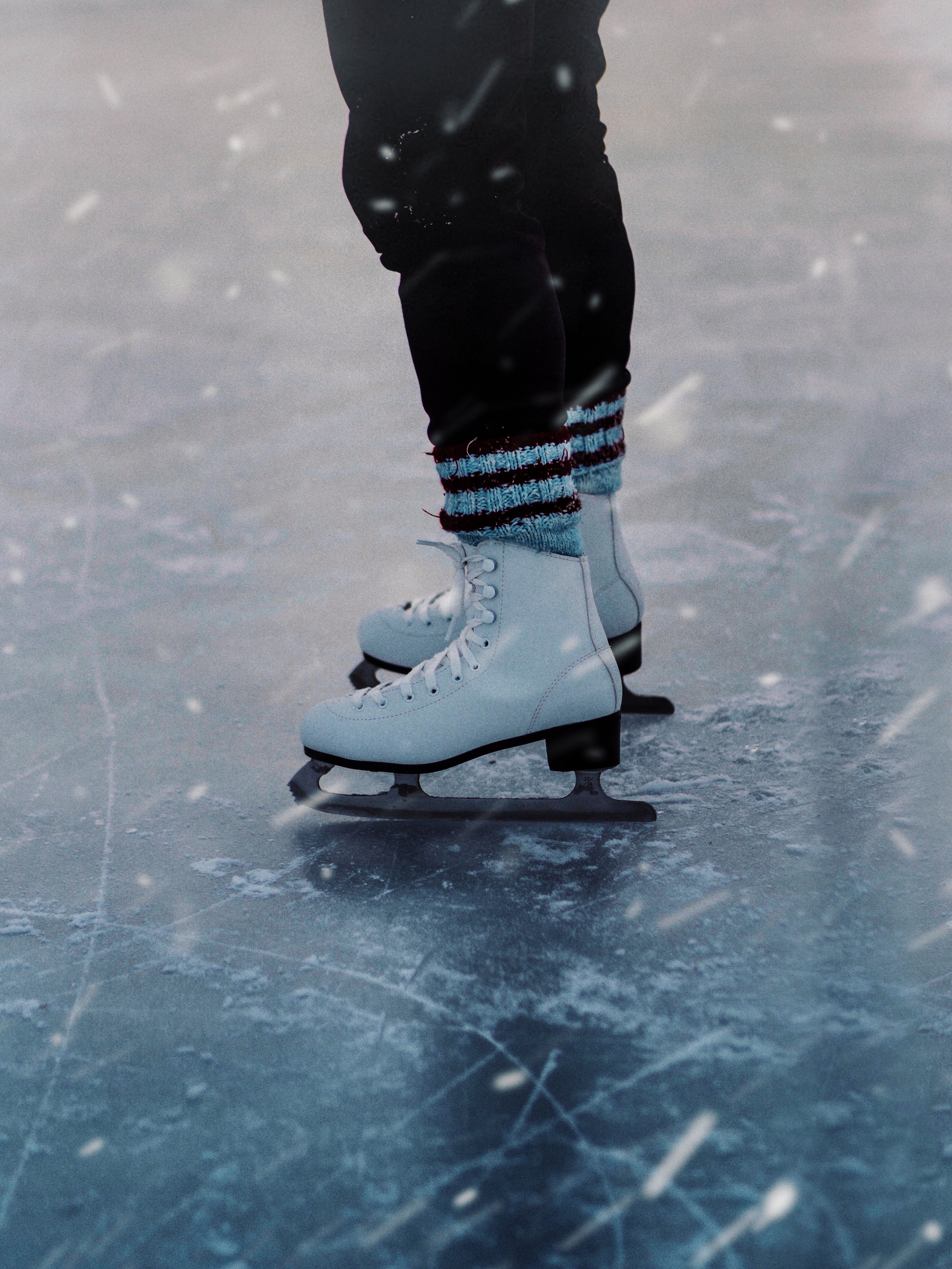 pexels image credit to Gantas Vaiciulenas. Image of two feet in ice skates on a frozen lake