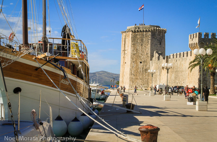 Image credit to Noel Morata. Image of large boat docked on the harbour in Trogir with building in background and promenade in front.