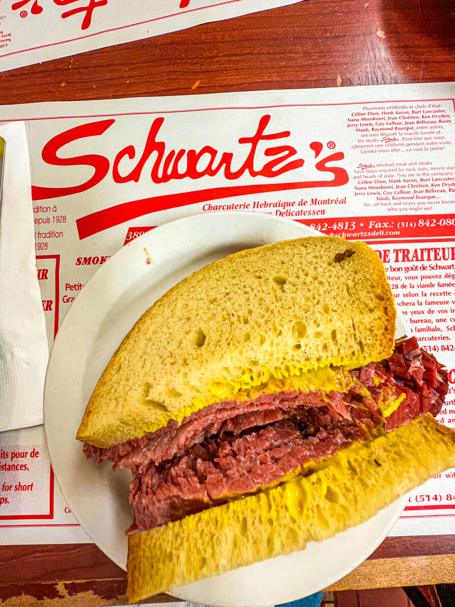 Image of Schwartz smoked meat sandwich on a white plate over the place mat of Schwartz's