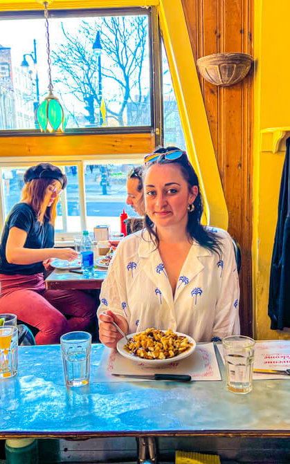 Image of Shireen posing with Poutine inside PATATI PATATA poutinery in Montreal Canada on Montreal Food Tour