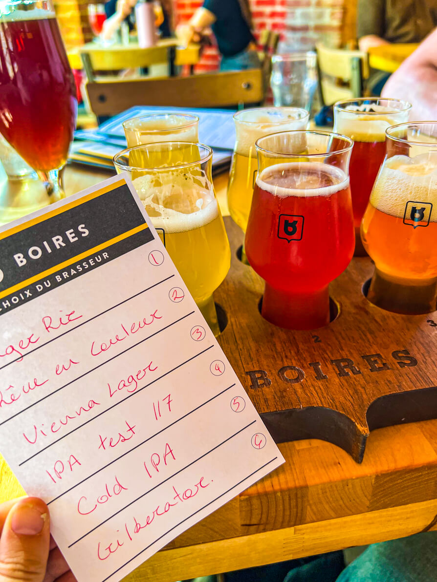 Image of flight at beer in micro brewery in Montreal Canada with a list of beer names held up