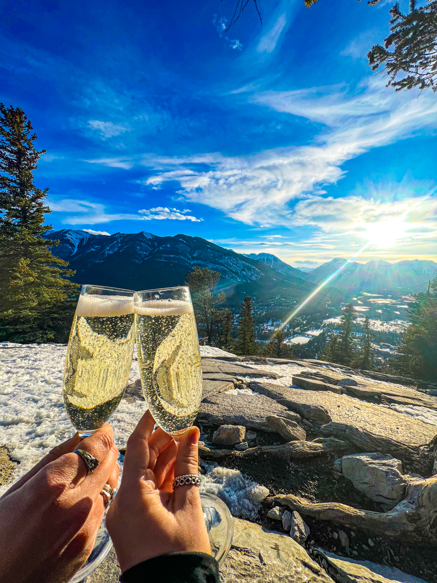 Two champagne glasses with view over mountains from Tunnel Mountain trail