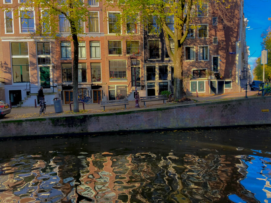 Authentic street scene of Rembrandtplein in Amsterdam, featuring the statue of Rembrandt and surrounding cafés